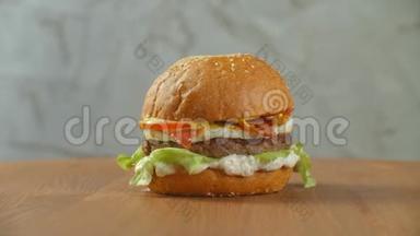 一个汉堡包在一块板上，炸薯条散落一地。特写美味的新鲜自制汉堡配生菜、奶酪